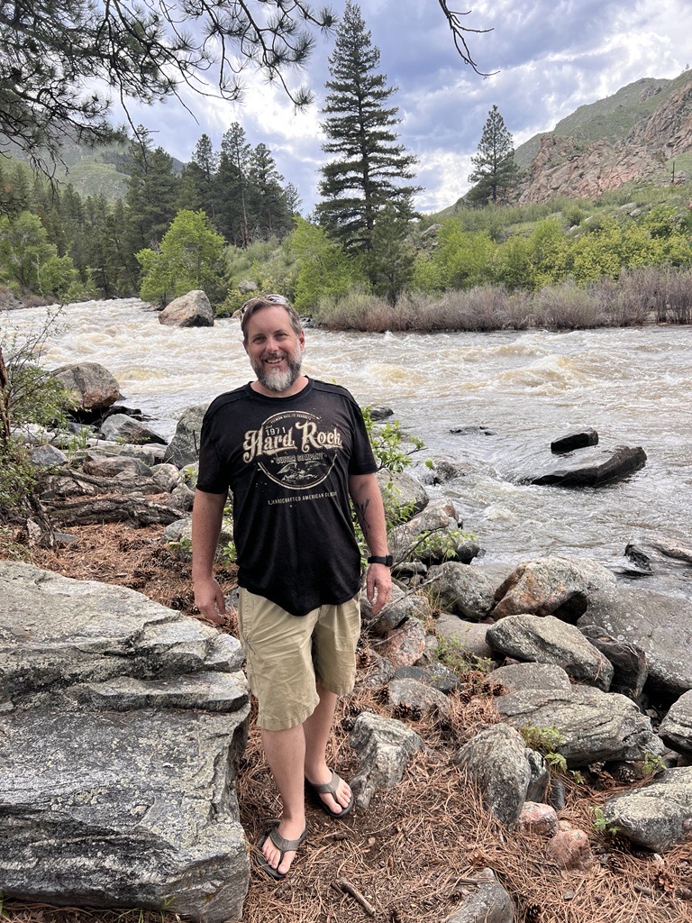 Robert Wiest Attorney at Law in Northern Colorado standing by river on Colorado hike